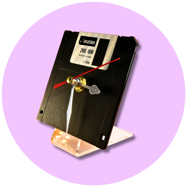 Coming Soon A vintage floppy disk transformed into a clock, mounted on a clear stand.